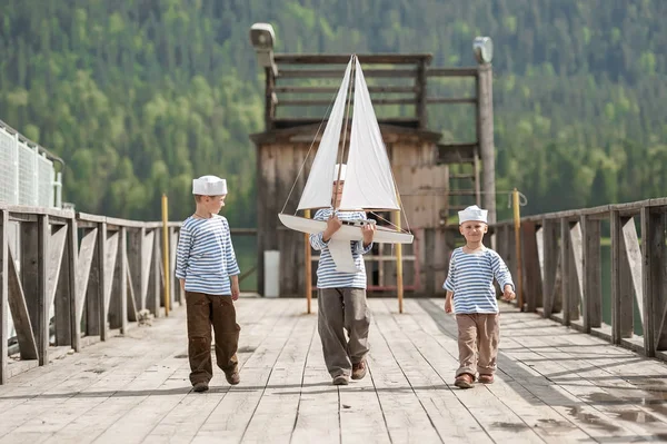 Chłopcy żeglarze z modelami jachtów na nabrzeżu jeziora górskiego — Zdjęcie stockowe
