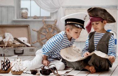 Bir korsan kaptan gibi giyinmiş çocuklar ve seyahat haritası okuyun