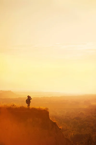 Menino com turista em um penhasco ao pôr do sol — Fotografia de Stock