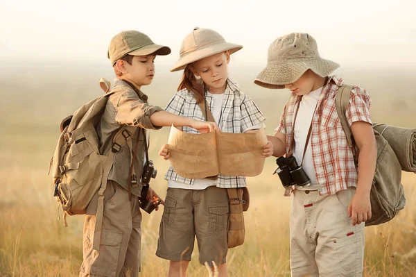 Group of kids travelers read a map at sunset — Stock Photo, Image