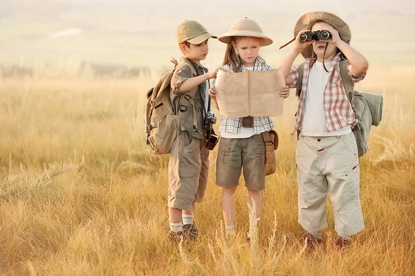 Grupo de crianças viajantes ler um mapa ao pôr do sol — Fotografia de Stock