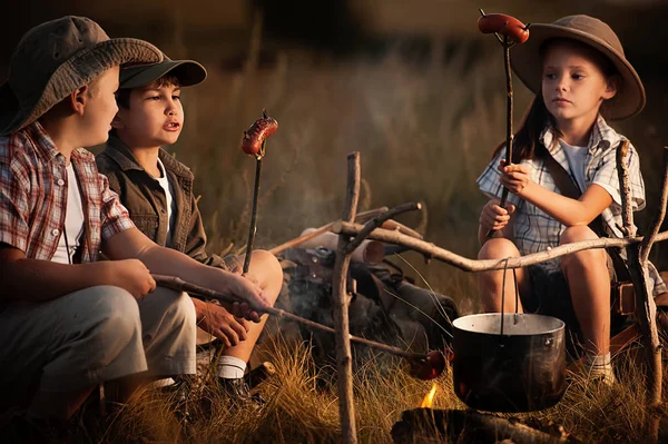 Group of children sitting around the campfire travelers — Stock Photo, Image