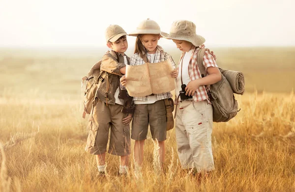 Grupo de niños viajeros leen un mapa al atardecer —  Fotos de Stock