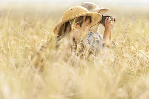 Ragazzi che guardano attraverso il binocolo in una spessa erba grigia — Foto Stock