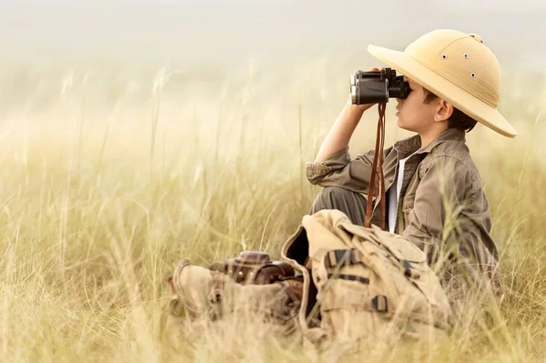 男孩在厚厚的灰色草地上透过望远镜看 — 图库照片