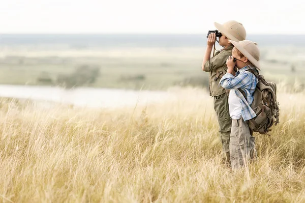 Barn med turister som tittar genom kikare i fjärran på branten — Stockfoto