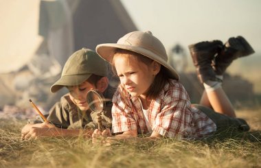 İki çocuk yeryüzündeböcekleri ve bitkileri keşfediyor.