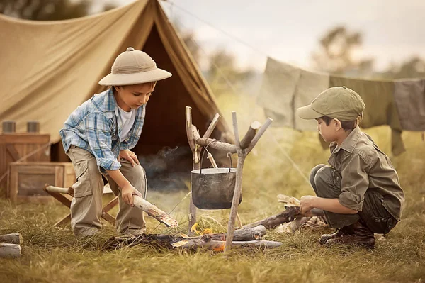 Twee van de kinderen zitten rond het kampvuur reizigers — Stockfoto