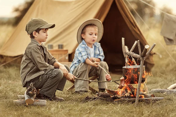 Twee van de kinderen zitten rond het kampvuur reizigers — Stockfoto