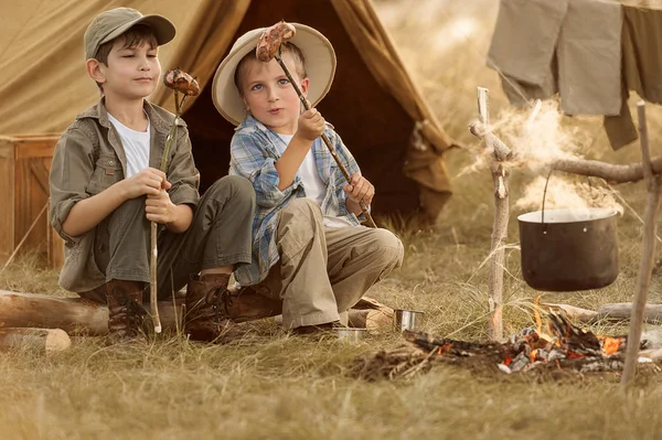 Two of children sitting around the campfire travelers