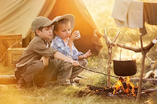 两个孩子坐在篝火旅行者身边 — 图库照片