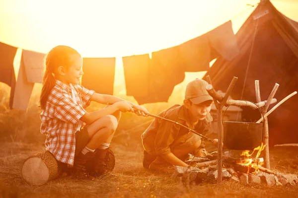 Twee van de kinderen zitten rond het kampvuur reizigers — Stockfoto