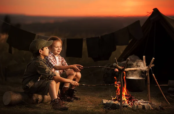 Kamp ateşi yolcularının etrafında oturan iki çocuk — Stok fotoğraf