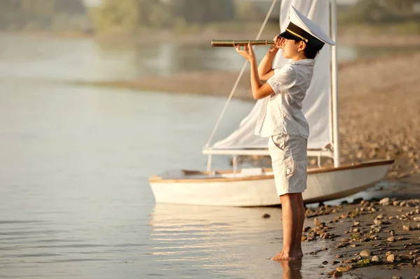 Kapitan chłopiec patrząc przez teleskop na jeziorze — Zdjęcie stockowe