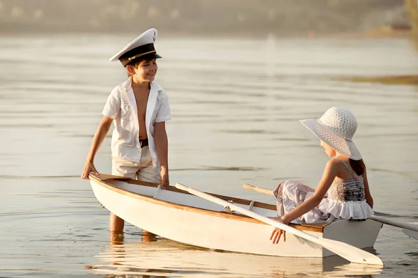 Junge mit einem Mädchen, das auf einem Boot über den See rudert — Stockfoto