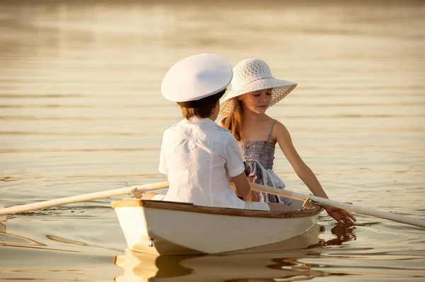 Boy with a girl floating on a boat rowed across the lake — Stock Photo, Image