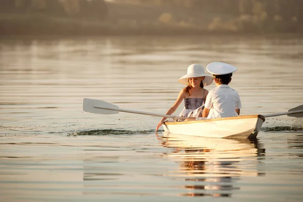 Junge mit einem Mädchen, das auf einem Boot über den See rudert — Stockfoto