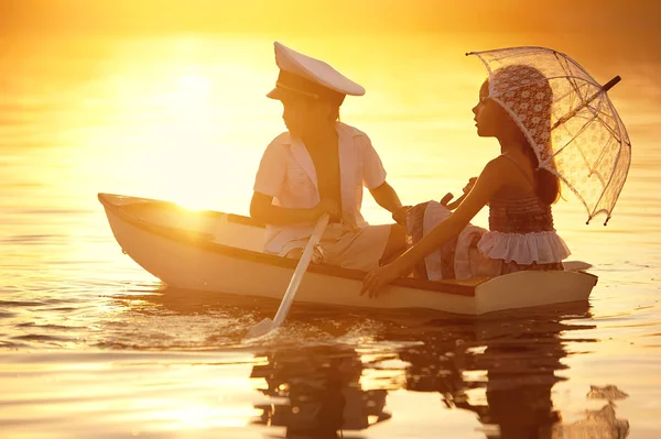 Boy with a girl floating on a boat rowed across the lake — Stock Photo, Image
