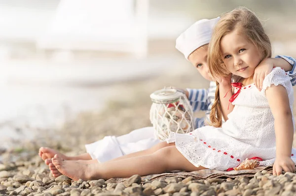 Мальчик с девушкой, сидящей на пляже и смотрящей вдаль — стоковое фото