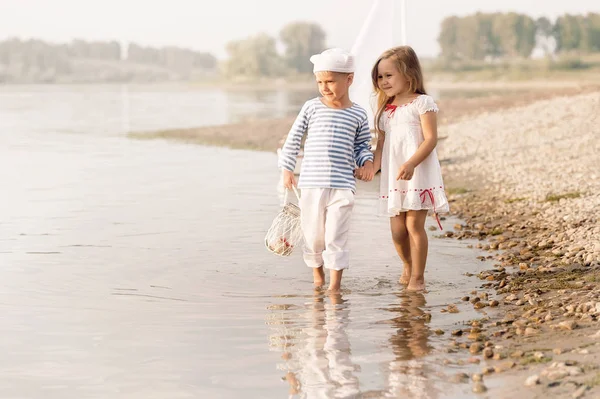 Boy with girl walking along the shore of the lake — Stock Photo, Image