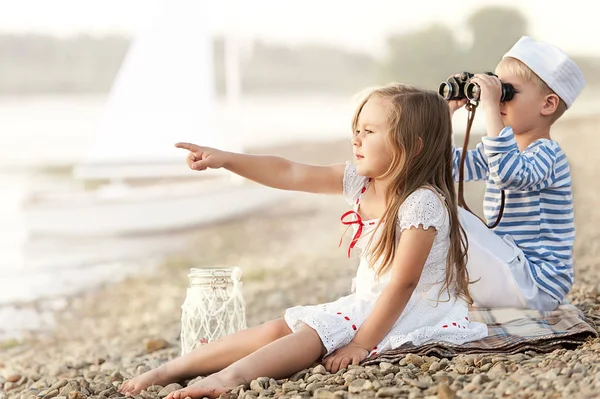 Niño con una chica sentada en la playa y mirando a la distancia — Foto de Stock