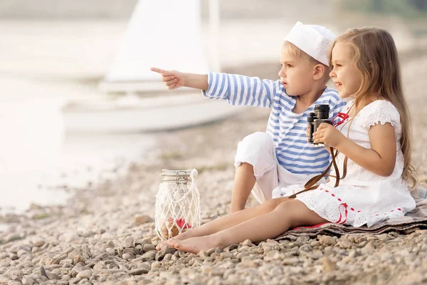 Jongen met een meisje zittend op het strand en op zoek naar de afstand — Stockfoto