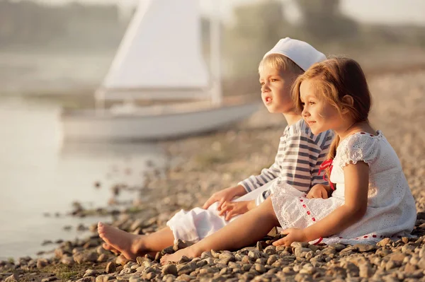 Garçon et fille assis sur le bord du lac et regarder le coucher du soleil — Photo