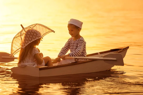 Boy with a girl floating on a boat rowed across the lake — Stock Photo, Image