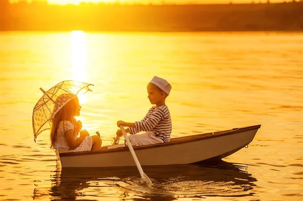 Garçon avec une fille flottant sur un bateau ramé à travers le lac — Photo