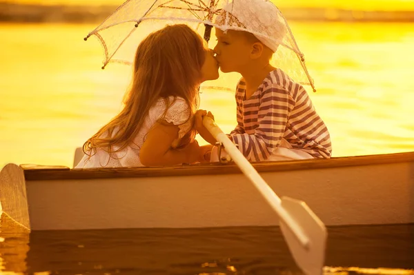 Junge küsst ein Mädchen und rudert mit dem Boot über den See — Stockfoto