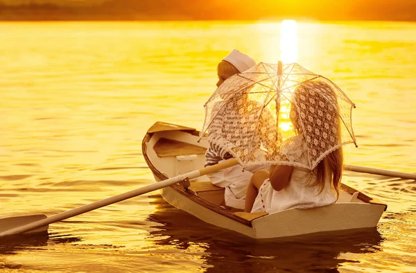 Garçon avec une fille flottant sur un bateau ramé à travers le lac — Photo