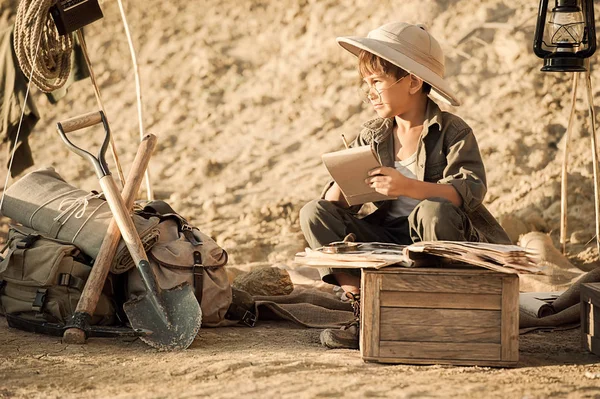 Boy archaeologist take notes in a notebook on the excavations conducted