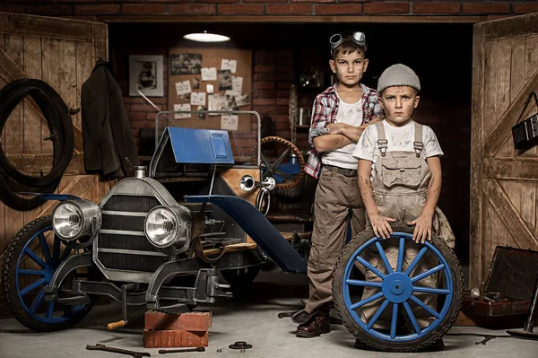 Meninos-mecânica no carro com a roda na garagem — Fotografia de Stock