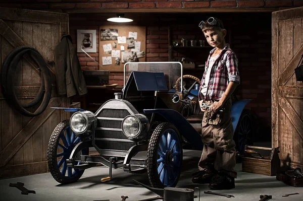 Junger Mechaniker repariert das Auto in der Dämmerung in der Garage — Stockfoto