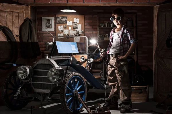 Jovem mecânico com um soldador no carro na garagem — Fotografia de Stock