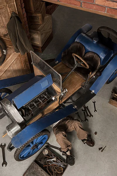 Парень механик ремонт ретро автомобиля в гараже — стоковое фото