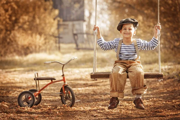 Liten pojke med leksaker på en gunga — Stockfoto