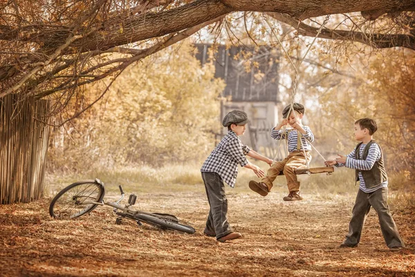 Barn gungande på gungor sommardag — Stockfoto