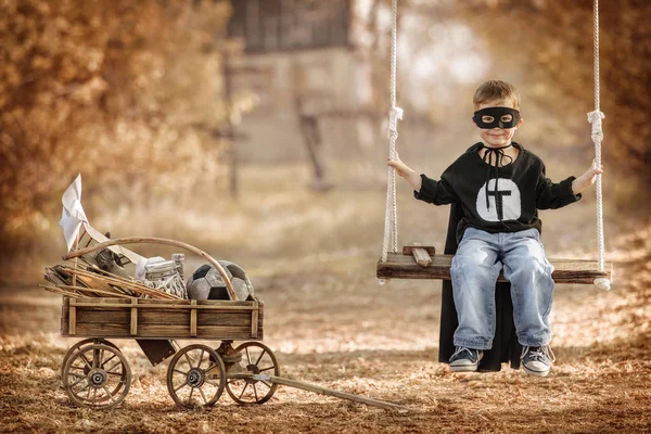 Kleine superheld swingende op een schommel — Stockfoto