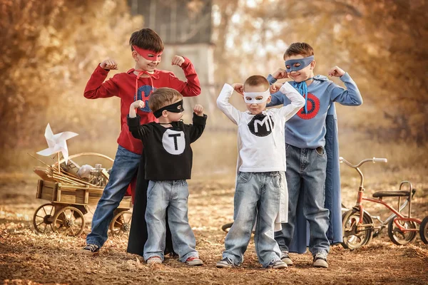 Czterech chłopców odgrywa superbohatera na placu zabaw — Zdjęcie stockowe