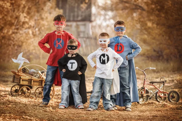 Quatro garotos jogam um super-herói no playground — Fotografia de Stock