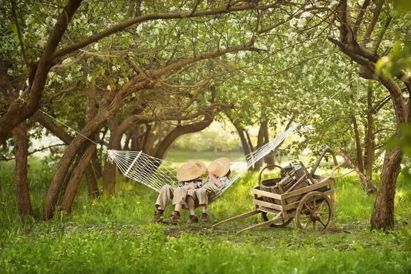 Genç bahçıvanlar işten sonra ağaçların altında bir hamakta dinleniyor. — Stok fotoğraf