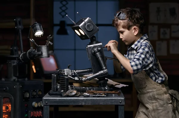 Молодой механик чинит робота в мастерской — стоковое фото