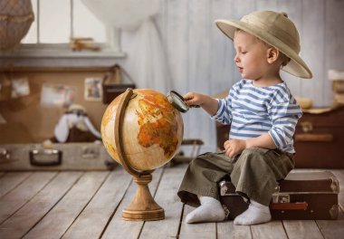 Seyahat güzergahlarında bir dünya planlayan turist şeklinde küçük bir çocuk.