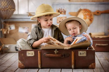 Turist kılığındaki iki çocuk, valizinde otururken çektiği fotoğrafları görüyor.