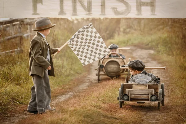 Finish of competition between the two little boys racers on homemade wooden car. Retouch for retro
