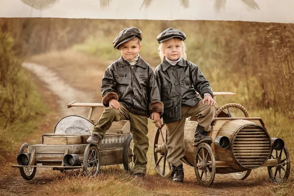 在秋天的雨天 有三个小男孩在乡村风景的背景下竞相驾驶简易木车 复古重触 — 图库照片