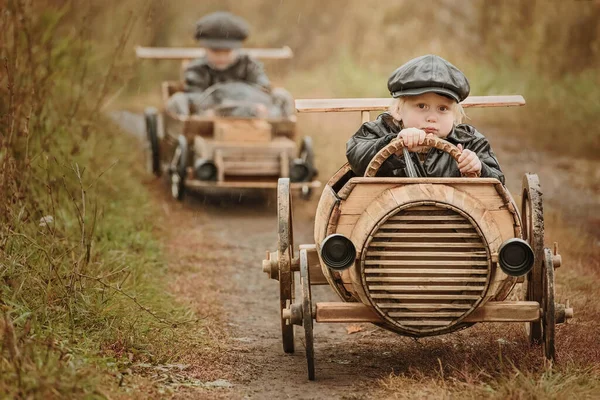 2人の男の子 ライダーは農村部の道路上の自家製の木製の車で互いに競争する レトロのためのレタッチ — ストック写真