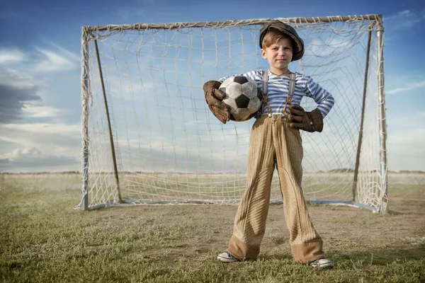 Portrait of a young goalkeeper with a ball at the gate