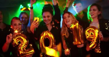 Mutlu yeni yıl 2019. Gençler bir gece kulübünde bengal ışıklar ateş ediyorlar. Onlar New 2019 kutluyoruz